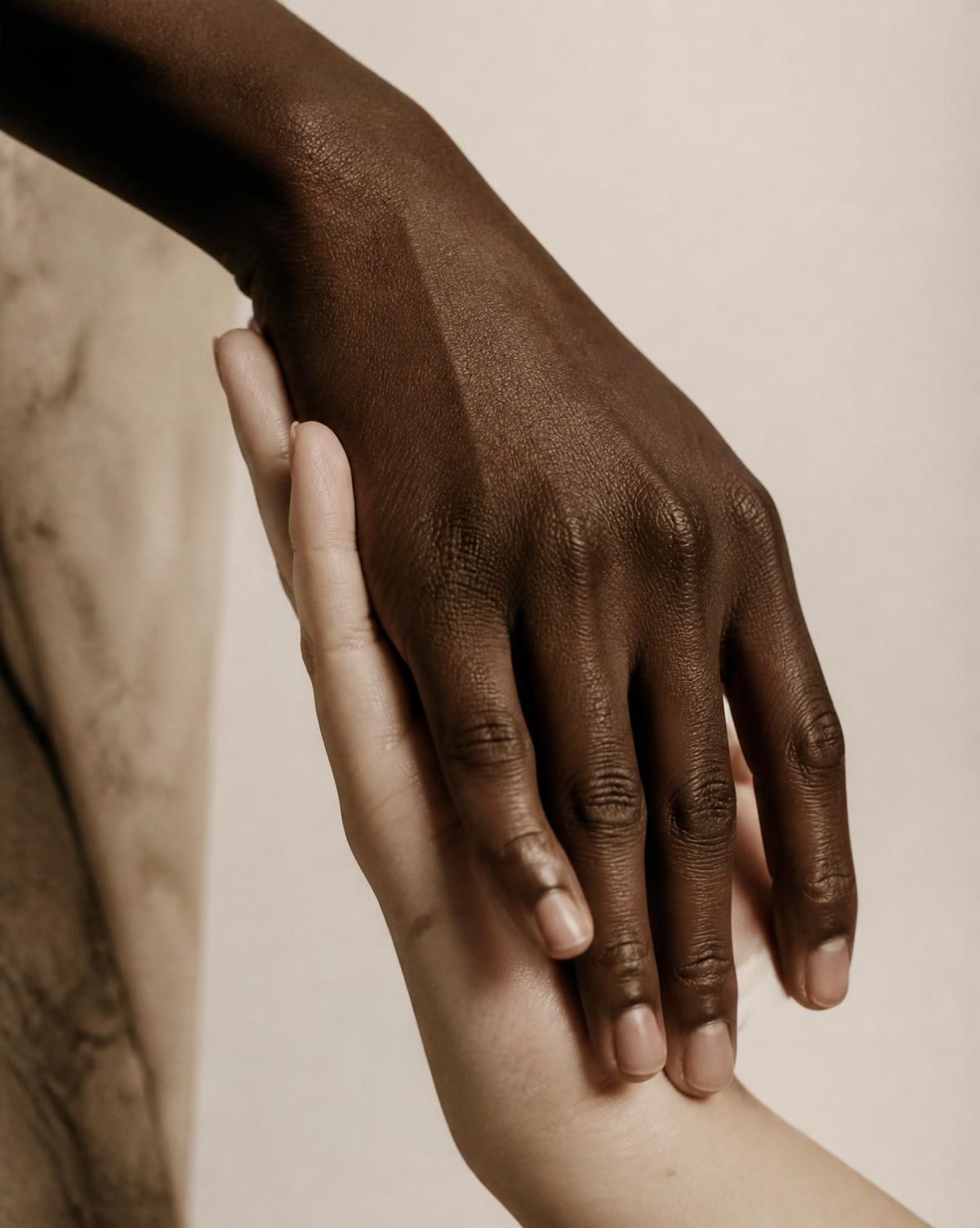 Two hands of different skin tones resting together