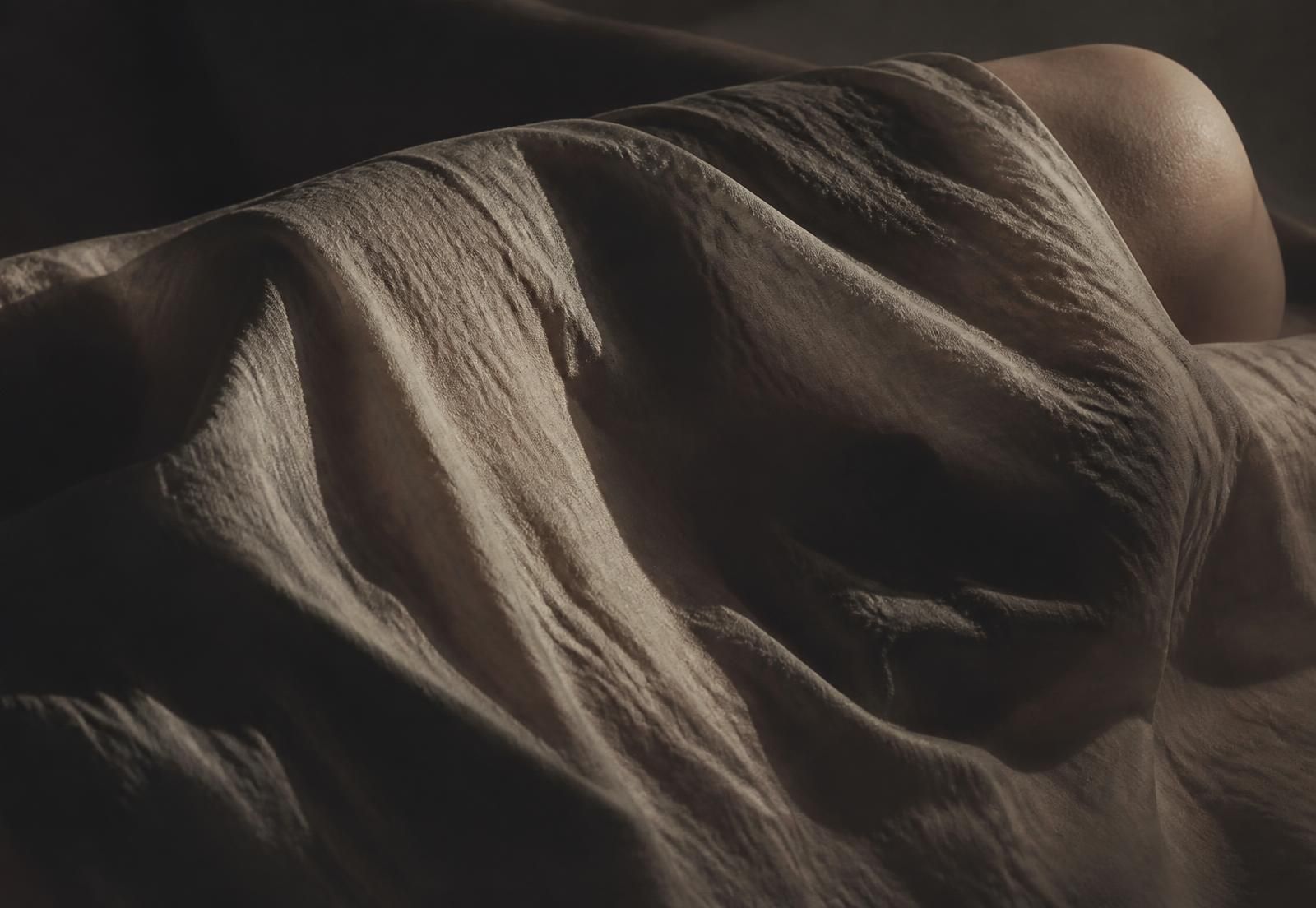Folds of fabric across an abstract human form, lit from the side